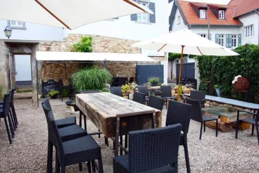 Innenhof der 0815 Wein - Lounge mit Bestuhlung und weißen Sonnenschirmen.