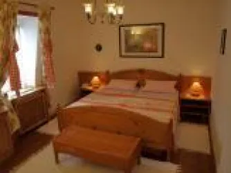 Ein gemütliches Schlafzimmer mit einem Doppelbett und Holzmöbeln. Die Wände sind in warmen Farben gehalten, und es gibt eine angenehme Beleuchtung.