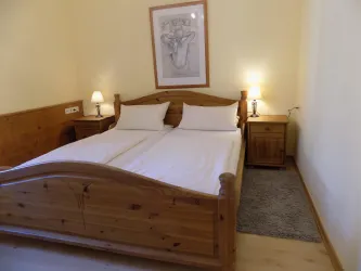 Ein einfaches Schlafzimmer mit zwei Einzelbetten und warmem Holzdekor. Die Wände sind in einem sanften Gelbton gehalten, ergänzt durch gemütliche Nachttische und beleuchtete Lampen.