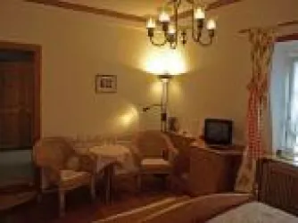Ein gemütliches Zimmer mit einem Kronleuchter und zwei Stühlen. Es gibt auch einen kleinen Tisch und einen Fernseher.