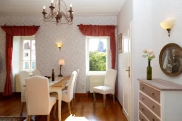 Ein helles Esszimmer mit einem eleganten Tisch und weißen Stühlen. Große Fenster bieten einen schönen Blick ins Grüne.