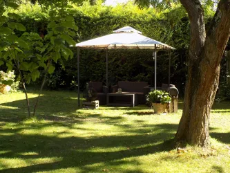 Ein gemütlicher Garten mit einer überdachten Sitzecke. Die grüne Umgebung sorgt für eine entspannte Atmosphäre.