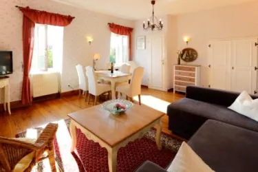 Ein helles Wohnzimmer mit einem gemütlichen Sofa und einem eleganten Esstisch. Große Fenster sorgen für viel Tageslicht und eine einladende Atmosphäre.