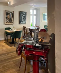 Innnenraum des Restaurants mit Bildern an der Wand, Stühlen und Tischen