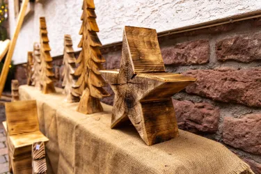 Holzfiguren in Form von Tannenbäumen und einem Stern stehen auf einem Tisch. Die dekorativen Stücke sind handwerklich verarbeitet und verleihen eine festliche Atmosphäre.
