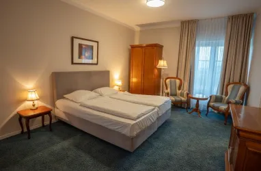 Großes Doppelzimmer mit einm Doppelbett, einem Schrank, 2 Sesseln und einem Tisch