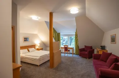 Großes Doppelzimmer mit Fernseher und Sitzecke. Ein Schreibtisch mit Blick in die Weinberge