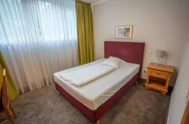 Einzelzimmer mit Bett, Schrank und Schreibtisch