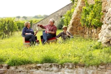 Fam. Bohnenstiel sitzend in den Weinbergen mit einem Glas Wein.