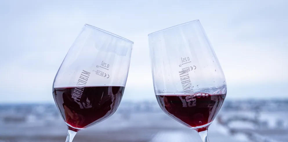 Rotweingläser vor verschneiten Weinbergen