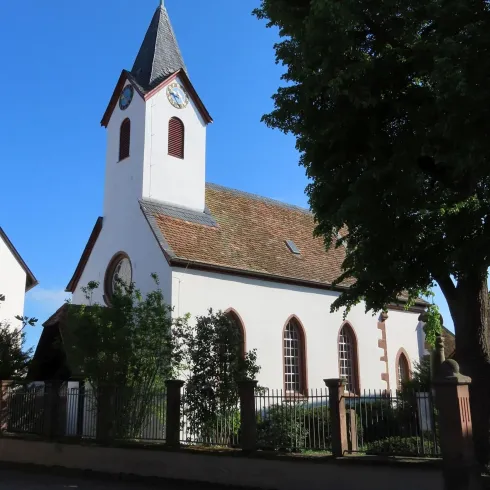<p><p>Protestantische Kirche Seiten- und Vorderansicht mit Baum im Vordergrund. Am Seitenschiff befinden sich drei weiße Rundbogenfenster. Darüber der Kirchturm.<br/></p></p>