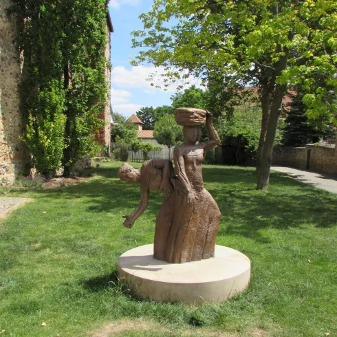 <p>Auf der Wiese vor der hist. Stadtmauer steht eine Skulptur mit zwei  Waschfrauen und Bäumen im Hintergrund.</p>