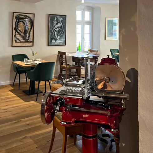 Innnenraum des Restaurants mit Bildern an der Wand, Stühlen und Tischen