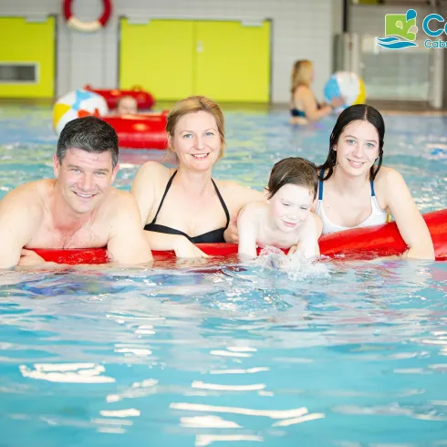 Eine Familie hat Spaß im Schwimmbecken. Sie schwimmen gemeinsam auf einem roten Schwimmreifen.