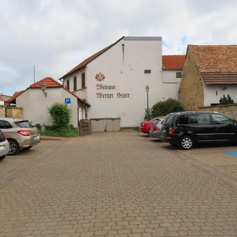 Ein Parkplatz direktz am Weingut Werner Storr, im hinteren Teil des Parkplatzes binfinden sich zwei Mülltonnen.