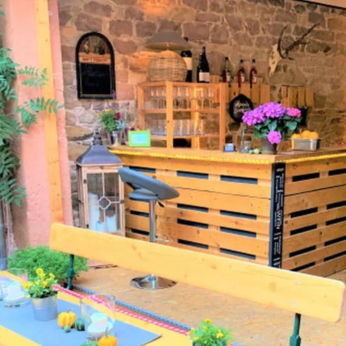 Eine Bar aus Holz. Die  Beleuchtung sorgt für eine entspannte Atmosphäre. Die Regale Hinter der Bar sind gefühlt mit Flaschen und Glässern.