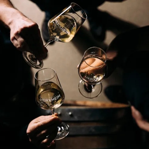 Drei sich zuprostende Weingläser der Winzergenossenschaft Herxheim/Bg.